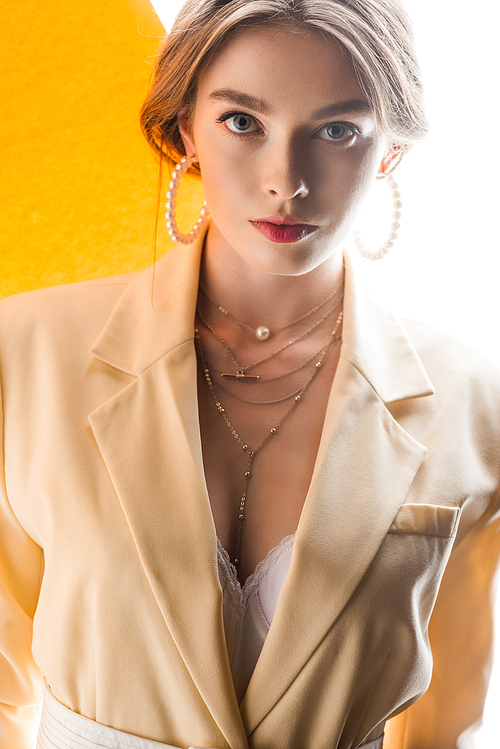 beautiful young woman in necklace and earrings  on orange and white