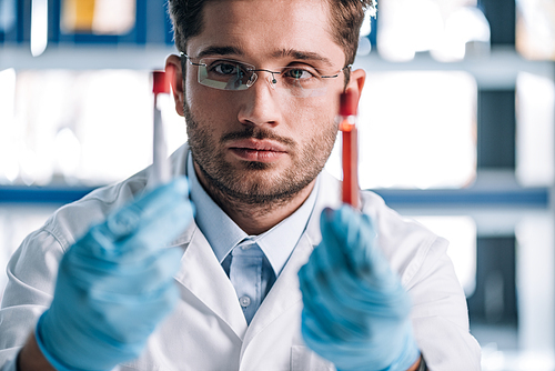 selective focus of handsome immunologist holding test tubes