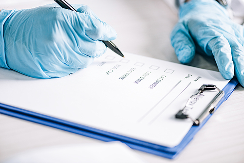 selective focus of immunologist holding pen near clipboard with checklist