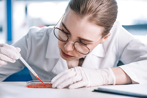 selective focus of attractive immunologist holding pipette with red liquid