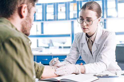 selective focus of attractive allergist holding syringe near man in clinic