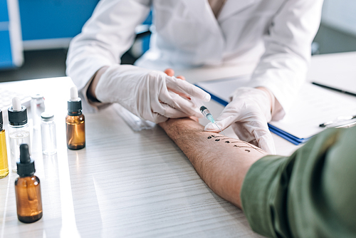 selective focus of allergist holding syringe near marked hand of patient