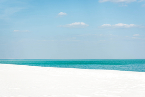beautiful beach with turquoise ocean, white sand and blue sky with white clouds