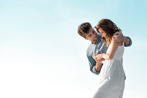 young couple hugging against blue sky