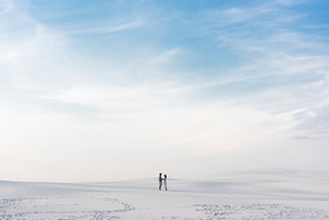 couple standing on sandy beach with blue sky