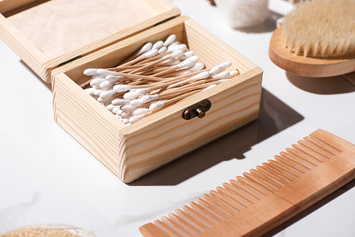 Selective focus of box of ear sticks, comb and Hair brush on white background, zero waste concept
