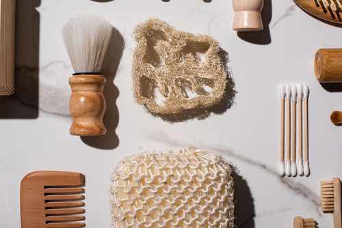 Top view of comb, toothbrushes, ear sticks, sponges, shaving brushes on white background, zero waste concept