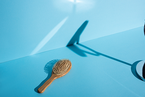 Wooden hair brush and shadow on blue background, zero waste concept