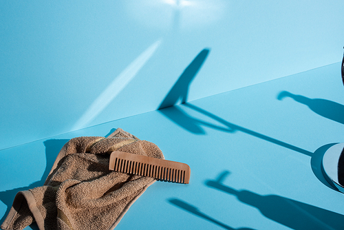 Comb on towel and shadows on blue background, zero waste concept