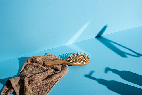 Hair brush on towel and shadows on blue background, zero waste concept