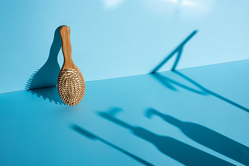 Hair brush and shadows on blue background, zero waste concept