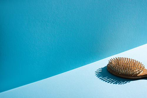 Wooden hair brush on surface on blue background, zero waste concept
