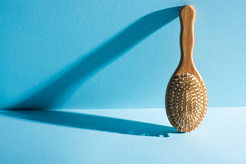 Wooden hair brush with shadow on blue background, zero waste concept