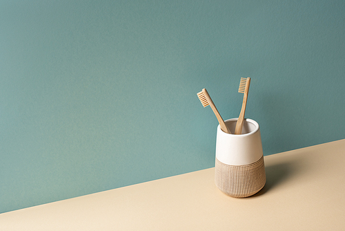 Toothbrushes in toothbrush holder on beige and grey, zero waste concept