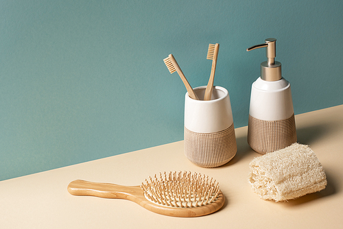 Toothbrushes, hair brush, liquid soap dispenser and sponge on beige and grey, zero waste concept