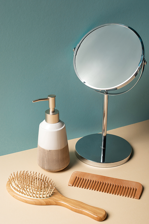 Comb, hair brush, liquid soap dispenser and mirror on beige and grey, zero waste concept