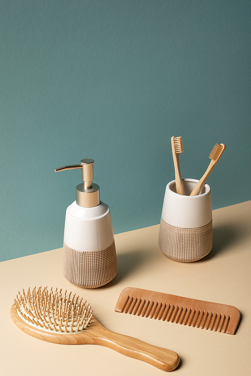 Toothbrushes, comb, liquid soap dispenser on beige and grey, zero waste concept