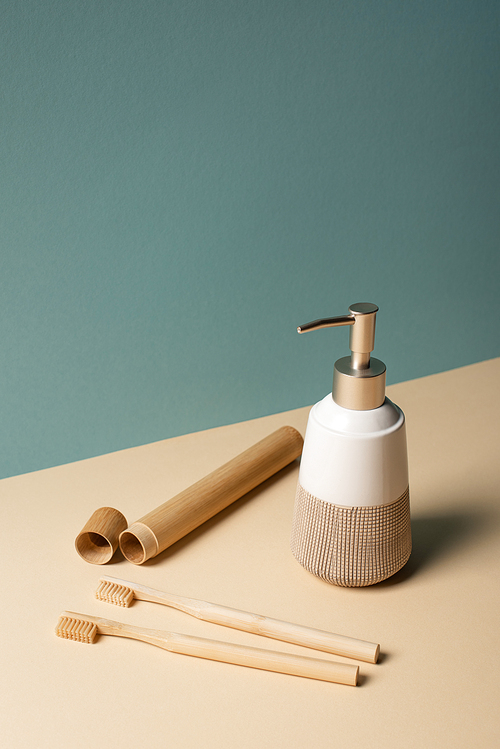 Toothbrushes, toothbrush case, liquid soap dispenser on beige and grey, zero waste concept