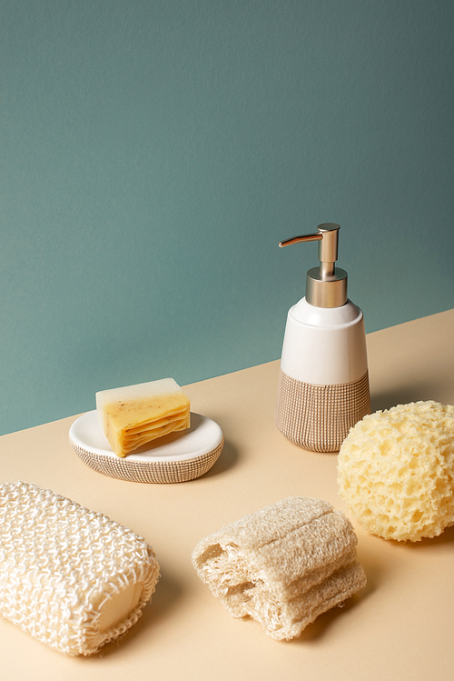 Sponges with liquid soap dispenser and soap dish on beige and grey, zero waste concept