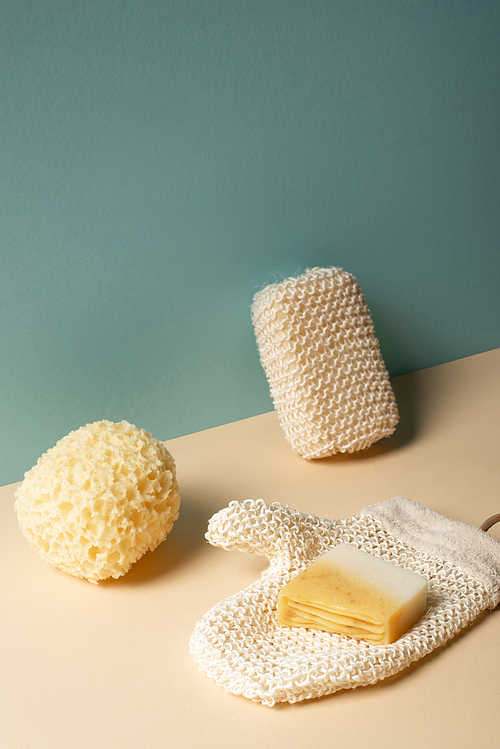 Sponges, exfoliating glove with soap on beige and grey, zero waste concept