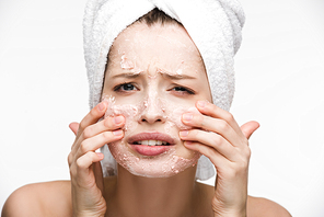 displeased girl with facial peeling mask touching face isolated on white