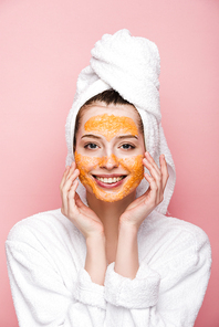 happy girl with citrus facial mask touching face while  isolated on pink