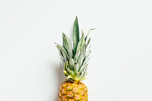 top view of ripe pineapple with green leaves on white background