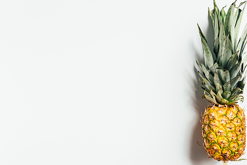 top view of ripe pineapple with green leaves on white background