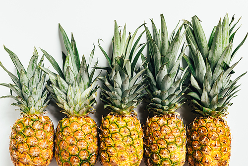 flat lay with fresh ripe pineapples with green leaves on white background