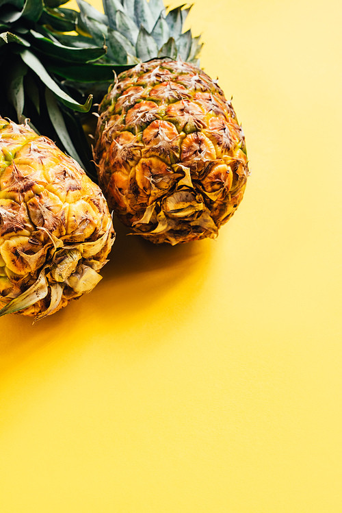 fresh ripe pineapples on yellow background with copy space
