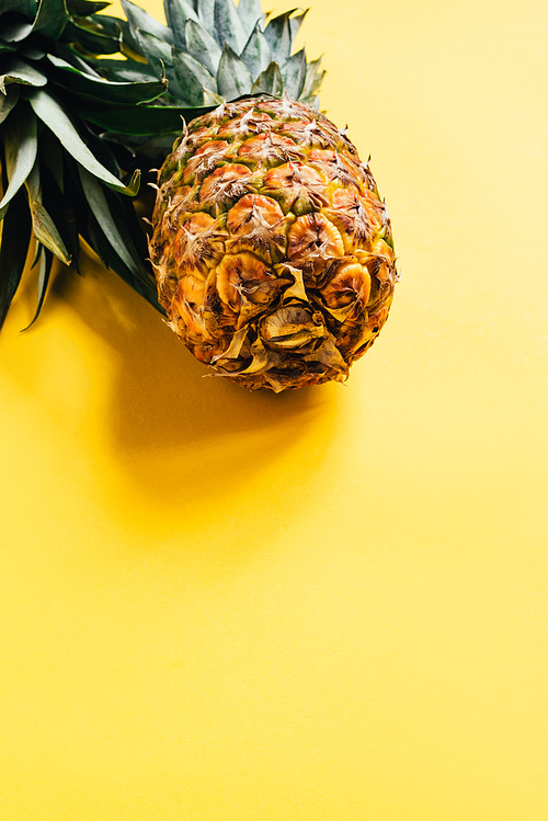 fresh ripe pineapple with green leaves on yellow background