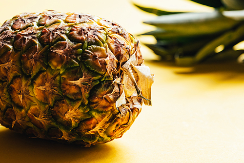 close up view of textured peel of pineapple on yellow background