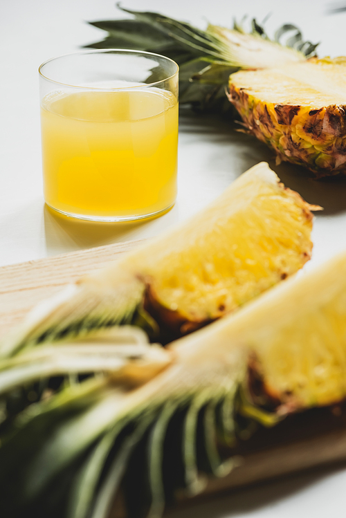 selective focus of fresh pineapple juice near cut delicious fruit on cutting board on white background