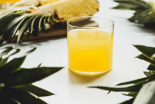 selective focus of fresh pineapple juice near cut delicious fruit on cutting board on white background