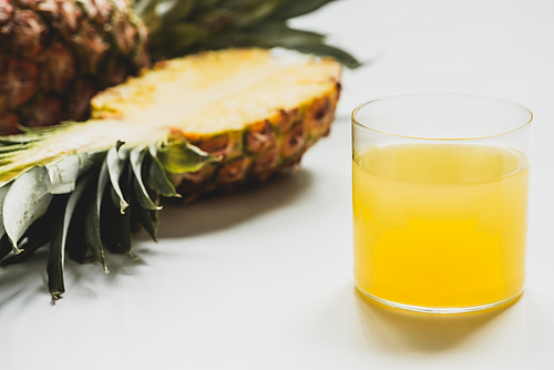 selective focus of fresh pineapple juice near cut delicious fruit on white background