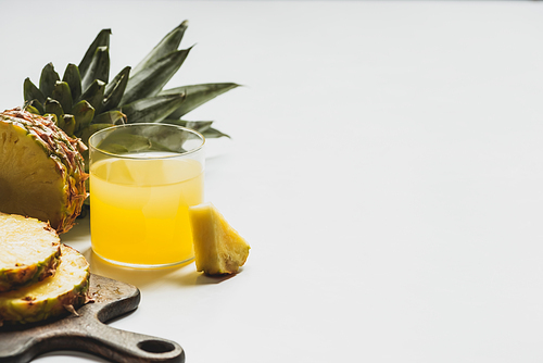 fresh pineapple juice near cut delicious fruit on wooden cutting board on white background