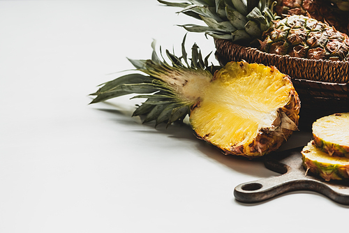 fresh cut delicious pineapple on wooden cutting board and in basket on white background