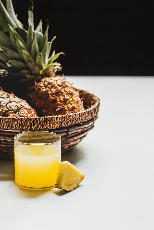 fresh pineapple juice near delicious fruit in basket on white background isolated on black