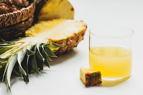 close up view of fresh pineapple juice near cut delicious fruit on white background