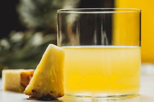 close up view of fresh pineapple juice near delicious fruit slice