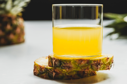 close up view of fresh pineapple juice on cut delicious slices on white background