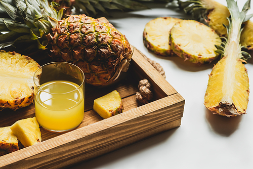 fresh pineapple juice and cut delicious fruit on wooden tray on white background