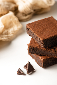 selective focus of delicious brownie pieces with dark chocolate on white background