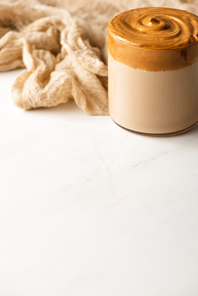 delicious coffee with foam near beige cloth on white background