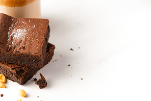 delicious brownie pieces with peanuts on white background