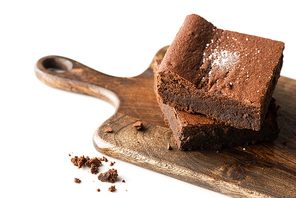delicious brownie pieces on wooden cutting board on white background
