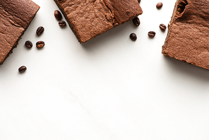 top view of delicious brownie pieces with coffee beans on white background
