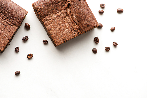 top view of delicious brownie pieces with coffee beans on white background