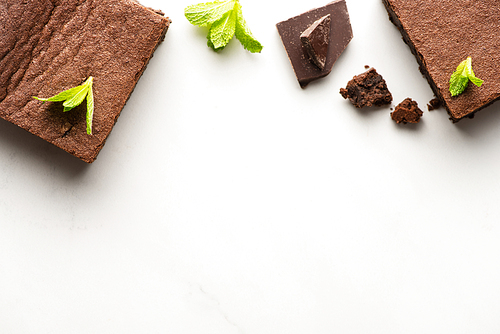 top view of delicious brownie pieces with mint and chocolate on white background