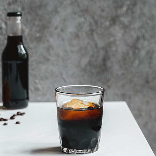 selective focus of cold brew coffee with ice in glass on white table